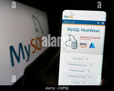 Stuttgart, 13.07.2023: Handybesitzer mit Website des relationalen Datenbankverwaltungssystems MySQL auf dem Bildschirm vor dem Logo. Stockfoto