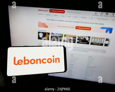 Stuttgart, Deutschland, 13.07.2023: Person, die ein Mobiltelefon mit dem Logo der französischen Kleinanzeigen-Firma Leboncoin auf dem Bildschirm vor dem Business Web hält Stockfoto