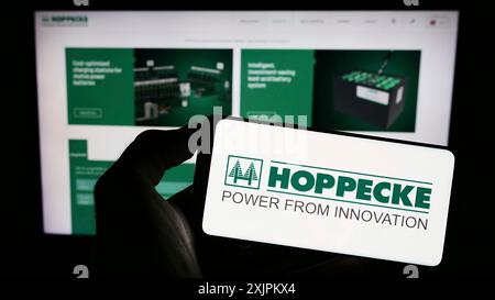 Stuttgart, 15.07.2023: Person mit Mobiltelefon mit Logo der deutschen Accumulatorenwerke Hoppecke vor dem Geschäft Stockfoto