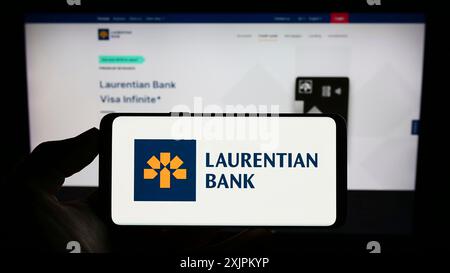 Stuttgart, Deutschland, 15.07.2023: Person, die ein Mobiltelefon hält, mit dem Logo des Finanzunternehmens Laurentian Bank of Canada (LBC) vor dem Bildschirm Stockfoto