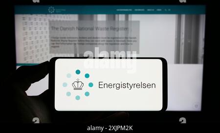 Stuttgart, 19.07.2023: Person, die ein Mobiltelefon mit dem Logo der dänischen Energieagentur Energistyrelsen auf dem Bildschirm vor der Webseite hält. Konzentrieren Sie sich auf Stockfoto