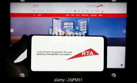 Stuttgart, 24.07.2023: Person, die ein Smartphone mit dem Logo der Emirati Roads and Transport Authority (RTA) auf dem Bildschirm vor der Website hält. Stockfoto