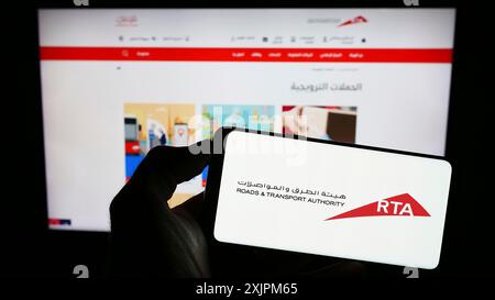 Stuttgart, 24.07.2023: Person mit Mobiltelefon mit Logo der Emirati Roads and Transport Authority (RTA) auf dem Bildschirm vor der Webseite. Stockfoto