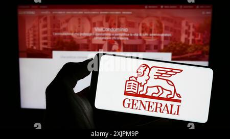 Stuttgart, 25.07.2023: Person, die ein Mobiltelefon mit dem Logo der Versicherungsgesellschaft Assicurazioni Generali Spa auf dem Bildschirm vor der Webseite hält. Stockfoto