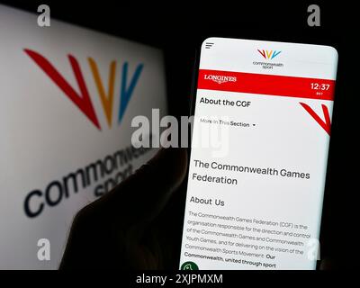 Stuttgart, Deutschland, 07-30-2023: Person, die ein Handy hält, mit Webseite der Organisation Commonwealth Games Federation (CGF) auf dem Bildschirm mit Logo. Fokus Stockfoto