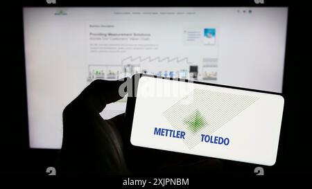 Stuttgart, Deutschland, 08.04.2023: Person mit Mobiltelefon mit Logo der Firma Mettler-Toledo International Inc. Auf dem Bildschirm vor dem Geschäft Stockfoto