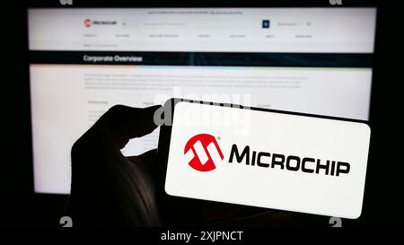 Stuttgart, Deutschland, 08.04.2023: Person, die ein Smartphone mit dem Logo des US-amerikanischen Halbleiterunternehmens Microchip Technology Inc. Auf dem Bildschirm hält Stockfoto