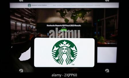 Stuttgart, Deutschland, 08.09.2023: Person, die ein Mobiltelefon hält, mit dem Logo der amerikanischen Kaffeehausfirma Starbucks Corporation vor dem Bildschirm Stockfoto