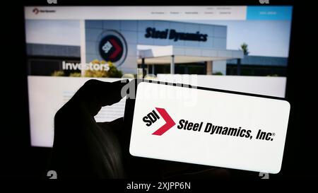 Stuttgart, Deutschland, 08.09.2023: Person, die ein Mobiltelefon mit dem Logo des US-amerikanischen Stahlherstellers Steel Dynamics Inc. Auf dem Bildschirm vor dem Geschäft hält Stockfoto