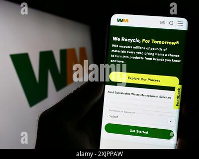 Stuttgart, Deutschland, 08.12.2023: Person, die ein Mobiltelefon hält, mit Webseite des US-Entsorgungsunternehmens Waste Management Inc. Auf dem Bildschirm vor dem Logo. Fokus Stockfoto