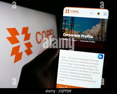 Stuttgart, Deutschland, 14.08.2023: Person, die ein Handy hält, mit Webseite der Firma Companhia Paranaense de Energia (Copel) auf dem Bildschirm mit Logo. Fokus Stockfoto