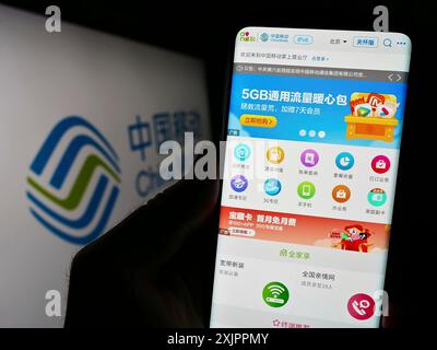 Stuttgart, Deutschland, 14.08.2023: Person, die ein Mobiltelefon hält, mit Webseite des Telekommunikationsunternehmens China Mobile Limited auf dem Bildschirm mit Logo. Fokus Stockfoto