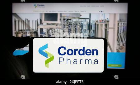 Stuttgart, Deutschland, 11.07.2023: Person mit Handy mit Logo des pharmazeutischen CDMO-Unternehmens CordenPharma vor der Business-Website. Konzentrieren Sie sich auf Stockfoto