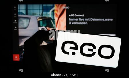 Stuttgart, Deutschland, 11.07.2023: Person mit Mobiltelefon mit Logo des deutschen Elektrofahrzeugunternehmens Next.e.GO Mobile SE vor der Webseite. Stockfoto