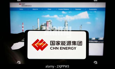 Stuttgart, Deutschland, 16.08.2023: Person, die ein Mobiltelefon mit dem Logo der Firma China Energy Investment Corporation auf dem Bildschirm vor dem Bildschirm hält Stockfoto