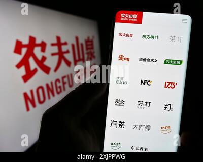 Stuttgart, Deutschland, 16.08.2023: Person, die ein Mobiltelefon hält, mit Webseite des chinesischen Unternehmens Nongfu Spring Company Limited auf dem Bildschirm mit Logo. Konzentrieren Sie sich auf Stockfoto