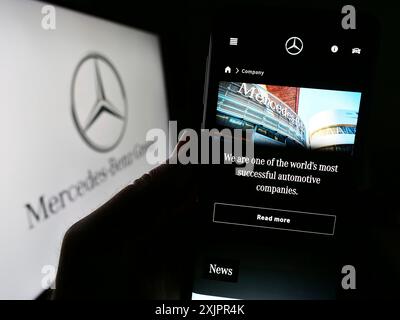 Stuttgart, 20.08.2023: Person, die ein Mobiltelefon hält, mit der Webseite des Automobilkonzerns Mercedes-Benz Group AG vor dem Logo auf dem Bildschirm. Fokus Stockfoto