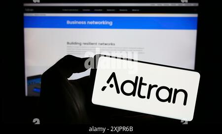 Stuttgart, Deutschland, 20.08.2023: Person, die ein Mobiltelefon mit dem Logo des US-Telekommunikationsunternehmens Adtran Inc. Vor dem Geschäft auf dem Bildschirm hält Stockfoto