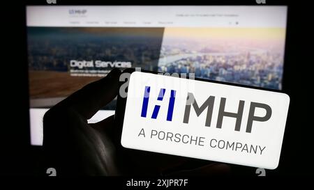 Stuttgart, 20.08.2023: Person mit Smartphone mit Logo der Firma MHP Management- und IT-Beratung GmbH auf dem Bildschirm vor der Website. Stockfoto