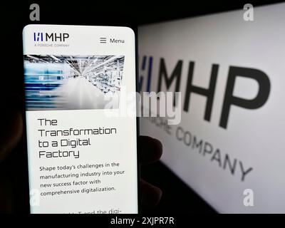 Stuttgart, 20.08.2023: Handybesitzer mit Webseite der Firma MHP Management- und IT-Beratung GmbH auf dem Bildschirm mit Logo. Konzentrieren Sie sich auf Stockfoto