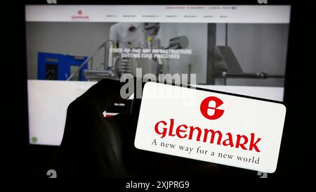 Stuttgart, Deutschland, 25.08.2023: Person, die ein Mobiltelefon mit dem Logo des indischen Unternehmens Glenmark Pharmaceuticals Limited auf dem Bildschirm vor der Webseite hält. Stockfoto