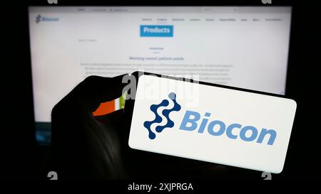 Stuttgart, Deutschland, 26.08.2023: Person, die ein Mobiltelefon mit dem Logo des indischen biopharmazeutischen Unternehmens Biocon Limited auf dem Bildschirm vor der Webseite hält. Stockfoto