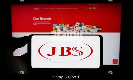 Stuttgart, Deutschland, 17.09.2023: Person, die ein Smartphone mit dem Logo des brasilianischen meerverarbeitenden Unternehmens JBS S.A. auf dem Bildschirm vor der Website hält. Stockfoto