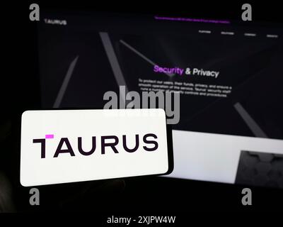 Stuttgart, Deutschland, 18.09.2023: Person mit Mobiltelefon mit Logo der schweizerischen Digital-Assets-Gesellschaft Taurus SA auf dem Bildschirm vor der Business-Website. Stockfoto