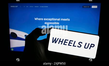 Stuttgart, Deutschland, 18.09.2023: Person, die ein Mobiltelefon mit dem Logo des US-Luftfahrtunternehmens Wheels Up Partners LLC auf dem Bildschirm vor dem Geschäft hält Stockfoto