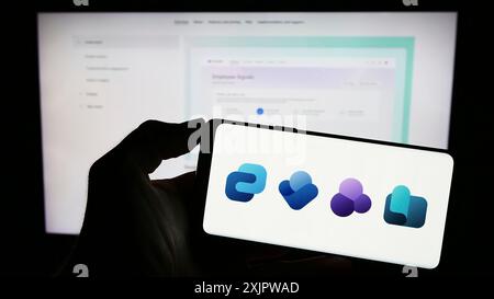Stuttgart, Deutschland, 22.09.2023: Person, die ein Mobiltelefon mit dem Logo der Employee Experience Plattform Microsoft Viva auf dem Bildschirm vor dem Unternehmen hält Stockfoto