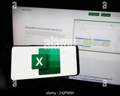 Stuttgart, Deutschland, 21.09.2023: Person, die ein Mobiltelefon mit dem Logo des Tabellenkalkulationseditors Microsoft Excel auf dem Bildschirm vor der Business-Webseite hält. Stockfoto