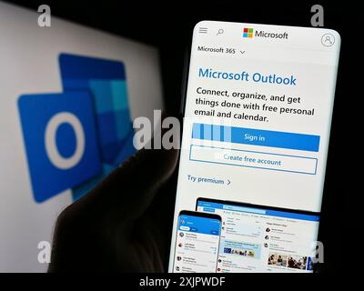 Stuttgart, Deutschland, 21.09.2023: Person, die ein Mobiltelefon hält, auf dem die Webseite der E-Mail-Software Microsoft Outlook vor dem Logo angezeigt wird. Konzentrieren Sie sich auf die Mitte Stockfoto