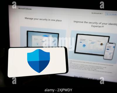 Stuttgart, Deutschland, 21.09.2023: Person, die ein Mobiltelefon hält, mit dem Logo der Sicherheitssoftware Microsoft Defender Antivirus auf dem Bildschirm vor der Webseite angezeigt wird. Stockfoto
