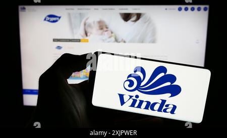 Stuttgart, Deutschland, 21.09.2023: Person, die ein Mobiltelefon mit dem Logo der Firma Vinda International Holdings Limited auf dem Bildschirm vor der Webseite hält. Stockfoto