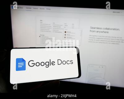 Stuttgart, Deutschland, 23.09.2023: Person mit Mobiltelefon mit Logo des Online-Textverarbeitungsprodukts Google Docs auf dem Bildschirm vor dem Unternehmen Stockfoto