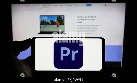 Stuttgart, Deutschland, 23.09.2023: Person mit Mobiltelefon mit Logo der Videobearbeitungssoftware Adobe Premiere Pro auf dem Bildschirm vor dem Unternehmen Stockfoto