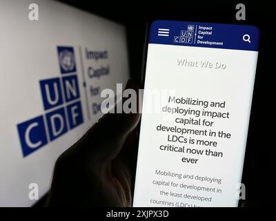 Stuttgart, Deutschland, 25.09.2023: Person, die ein Mobiltelefon hält, mit Website des Fonds der Vereinten Nationen für Kapitalentwicklung (UNCDF) vor dem Logo. Konzentrieren Sie sich auf Stockfoto