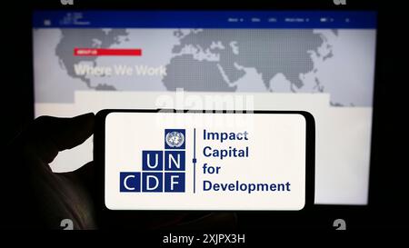 Stuttgart, Deutschland, 25.09.2023: Person mit Mobiltelefon mit Logo des Fonds der Vereinten Nationen für Kapitalentwicklung (UNCDF) vor der Webseite. Konzentrieren Sie sich auf Stockfoto
