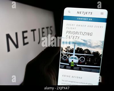 Stuttgart, 25.09.2023: Person mit Smartphone und Website des US-amerikanischen Business Jet-Unternehmens NetJets Inc. Vor dem Business-Logo. Konzentrieren Sie sich auf Stockfoto