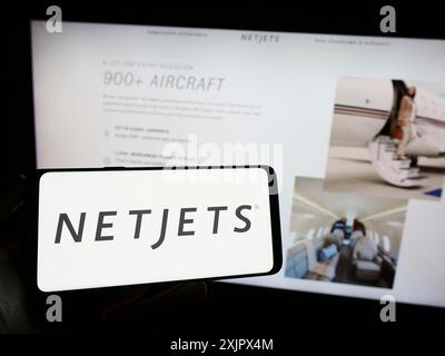 Stuttgart, 25.09.2023: Person, die ein Mobiltelefon mit dem Logo des US-amerikanischen Business Jet-Unternehmens NetJets Inc. Vor der Business-Website hält. Konzentrieren Sie sich auf Stockfoto