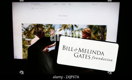 Stuttgart, 10.06.2023: Person mit Handy mit Logo der American Bill and Melinda Gates Foundation (BMGF) vor der Webseite. Konzentrieren Sie sich auf Stockfoto