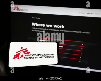 Stuttgart, 10.06.2023: Handybesitzer mit Logo der Wohltätigkeitsorganisation Ärzte ohne Grenzen vor der Webseite. Konzentrieren Sie sich auf Stockfoto