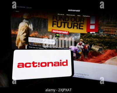 Stuttgart, 10.08.2023: Person mit Handy mit Logo der internationalen Wohltätigkeitsorganisation ActionAid vor der Webseite. Konzentrieren Sie sich auf Stockfoto