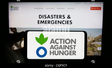 Stuttgart, 10.09.2023: Handybesitzer mit Logo der humanitären Organisation Aktion gegen den Hunger vor der Webseite. Konzentrieren Sie sich auf Stockfoto