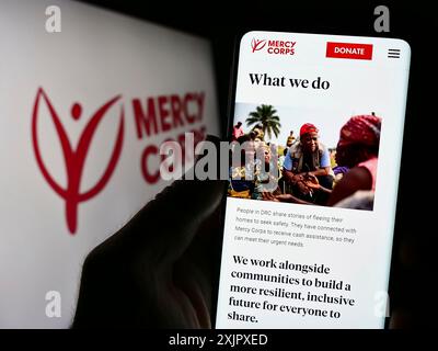 Stuttgart, Deutschland, 10.09.2023: Person, die ein Handy hält, mit Webseite der US-Hilfsorganisation Mercy Corps vor dem Logo. Konzentrieren Sie sich auf Stockfoto