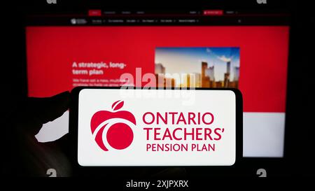 Stuttgart, 13.10.2023: Person mit Handy mit Logo der Organisation Ontario Teachers' Pension Plan Board (OTPP) vor der Webseite. Stockfoto