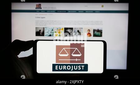 Stuttgart, 20.10.2023: Person mit Handy mit Logo der EU-Agentur für justizielle Zusammenarbeit in Strafsachen (Eurojust) vor der Webseite. Stockfoto