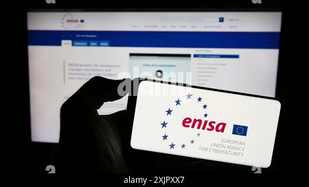 Stuttgart, Deutschland, 16.10.2023: Person mit Mobiltelefon mit Logo der Agentur der Europäischen Union für Cybersicherheit (ENISA) vor der Webseite. Konzentrieren Sie sich auf Stockfoto