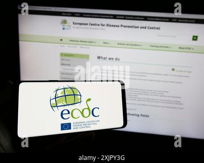 Stuttgart, 25.10.2023: Person mit Handy mit Logo des Europäischen Zentrums für die Prävention und die Kontrolle von Krankheiten (ECDC) vor der Webseite. Stockfoto