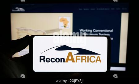 Stuttgart, 28.10.2023: Person mit Smartphone mit Logo der Firma Reconnaissance Energy Africa Ltd. (ReconAfrica) vor der Website. Stockfoto